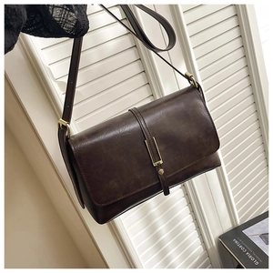 Détail du sac à bandoulière en similicuir marron foncé avec rabat et boucle en métal