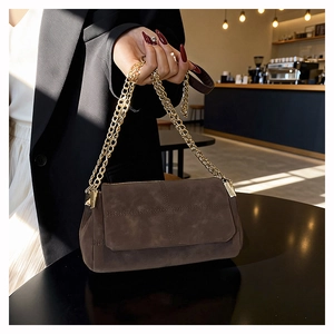 Detail of vintage brown suede crossbody bag with gold chain strap and cross stitching