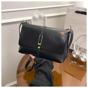 Gros plan sur un sac bandoulière plissé noir avec une boucle décorative en métal doré