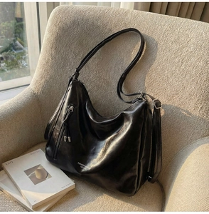 Macro shot of black oil-wax leather texture and side tassel on a large tote bag