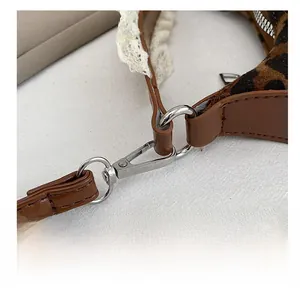 Macro detail of silver metal hook on leopard print bag with lace and leather strap