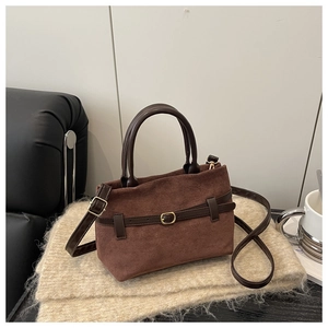 Détail d'un sac en daim marron vintage avec sangles en cuir et boucle dorée sur tricot