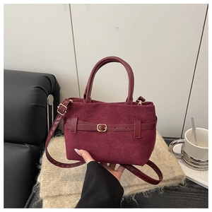 Détail de sac à main bordeaux en daim givré avec boucle décorative et double anse