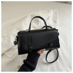 Detail of black vintage crossbody bag with scalloped flap and decorative buttons