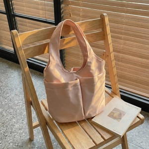 Sac seau en nylon rose avec deux poches avant et bandoulière pour usage quotidien
