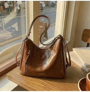 Close-up of brown vintage leather shoulder bag with fringe zipper and brand logo