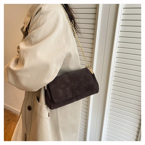 Detail of dark brown frosted crossbody bag with golden chain and cross-stitching