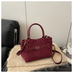 Détail du sac à main en daim bordeaux avec boucle dorée sur écharpe en tricot