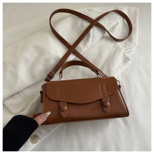 Close-up of brown vintage crossbody bag with flap and decorative double strap buckle