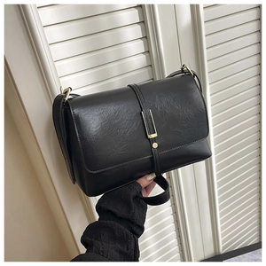 Détail d'un sac bandoulière noir vintage avec boucle dorée et texture cuir grainé