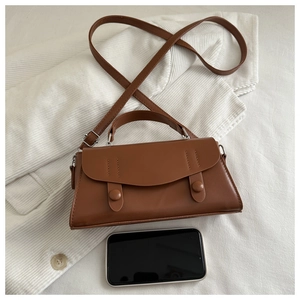 Top view of a small brown vintage crossbody bag with a smartphone for size reference