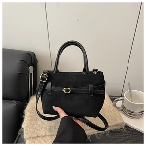 Détail d'un sac à main en daim noir avec sangle décorative et boucle en métal