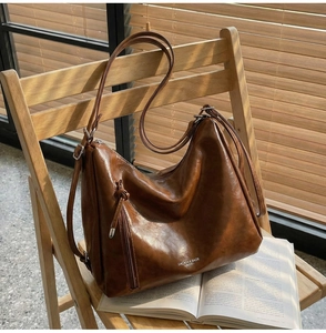 Brown vintage hobo bag on wooden chair with stylish side zipper and leather puller