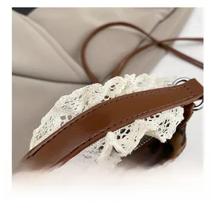 Dettaglio del manico in pelle marrone con pizzo bianco e trama della borsa leopardata