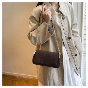 Detail of dark brown suede shoulder bag with vintage gold chain and cross stitching