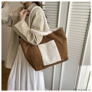 Detail of a large brown faux suede tote bag with white plush fleece handles and pocket