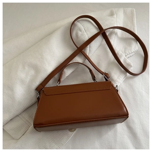 Close-up of brown matte leather handbag featuring clean stitching and adjustable strap