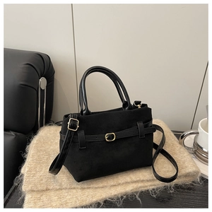 Détail d'un sac noir en suédine avec boucle dorée et poignées supérieures assorties