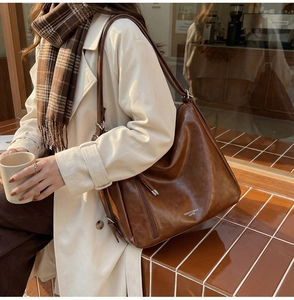 Close-up of vintage brown leather tote bag with fashion lettering and textured finish