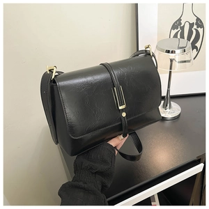 Gros plan du sac bandoulière noir rétro avec texture plissée et boucle dorée