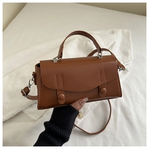 Close-up of caramel brown retro handbag with decorative buttons and stitching details