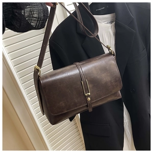 Gros plan d'un sac à bandoulière vintage marron foncé avec texture mate et fermoir aimanté