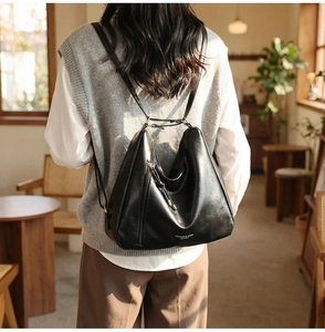 Detailed view of the shiny black leather backpack with metallic zippers and slim straps