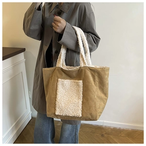 Detail of brown suede tote bag featuring white sherpa trim and front patch pocket design