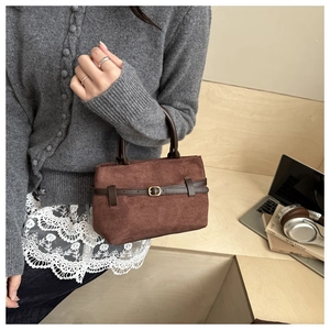 Detailed close-up of brown faux suede tote bag with decorative buckle on a desk