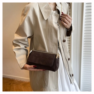 Detail of vintage brown suede crossbody bag with gold chain and cross stitching