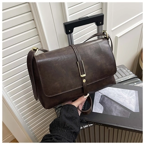Détail d'un sac à main vintage en cuir marron avec boucle dorée à côté d'une valise argent
