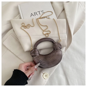 Détail d'un sac à main croissant bronze métallisé avec texture côtelée et chaîne dorée