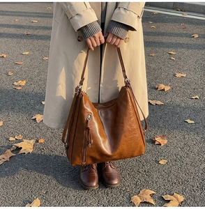 Detail shot of brown vintage PU leather tote with tassel and zipper in outdoor natural light