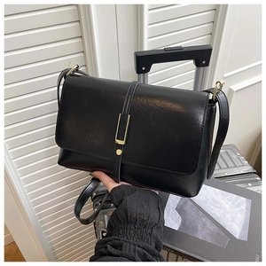 Détail d'un sac bandoulière en similicuir noir avec boucle en métal doré et grainage fin