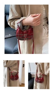 Red plaid crossbody bag with bows and white lace handle details in home setting