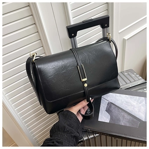 Détail du sac bandoulière en cuir grainé noir avec une élégante boucle en métal doré