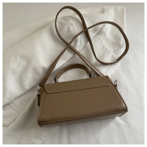 Detailed top view of a brown vintage leather handbag with adjustable strap on white fabric