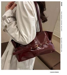 Detail of burgundy oil-wax leather shoulder bag with gold buckle and eyelet strap
