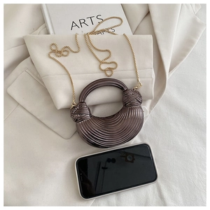 Détail du sac à main en croissant avec rayures métalliques et chaîne perlée dorée