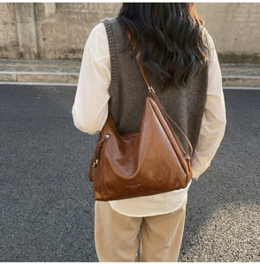 Outdoor street view of a large brown vintage leather tote bag with tassel detail