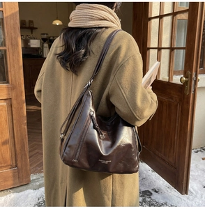 Detail of a large vintage brown faux leather shoulder bag with adjustable strap and zip