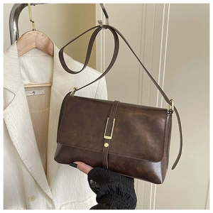 Détail d'un sac bandoulière marron vintage en cuir vieilli avec boucle en métal doré