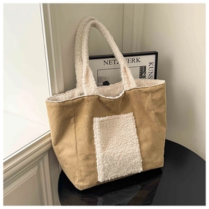 Detail of khaki suede tote bag with white faux fur pocket on a black polished table