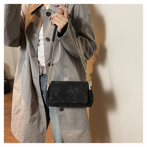 Close-up of minimalist black matte chain bag worn over the shoulder by a model