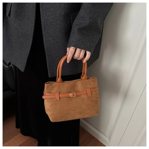 Détail du sac à main vintage en daim marron avec ceinture en cuir et boucle dorée