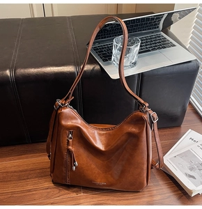 Detailed close-up of brown leather hobo bag with metal zipper and fashion branding