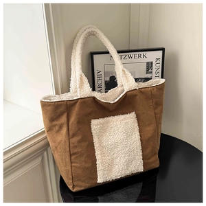 Detail of a brown suede tote bag with cream sherpa trim on a minimalist table
