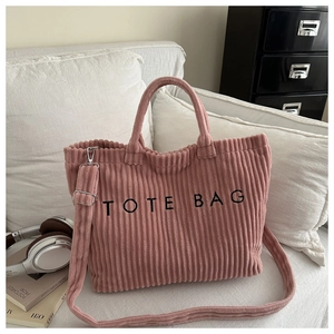 Pink corduroy tote bag detail showing dual straps and black embroidered text