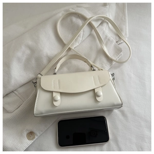 Detailed view of white leather crossbody bag with top handle and round decorative buckles