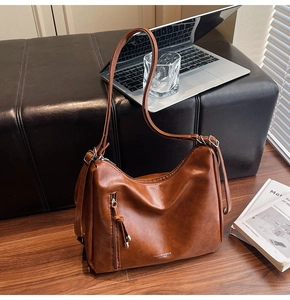 Detail view of brown PU leather hobo bag with adjustable strap and front zipper accent